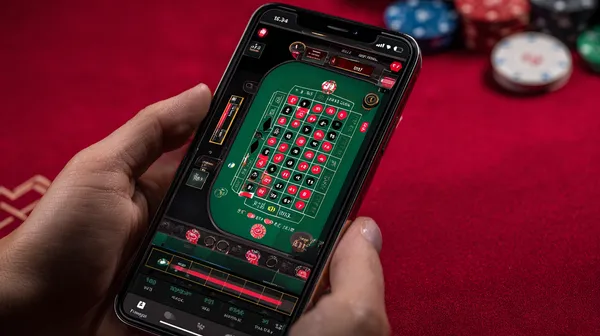 FB77 Mobile App — Your complete hub for casino and sports A man focused on his laptop with live stats in the background, highlighting the dedicated sports and gaming features of the FB77 mobile app.